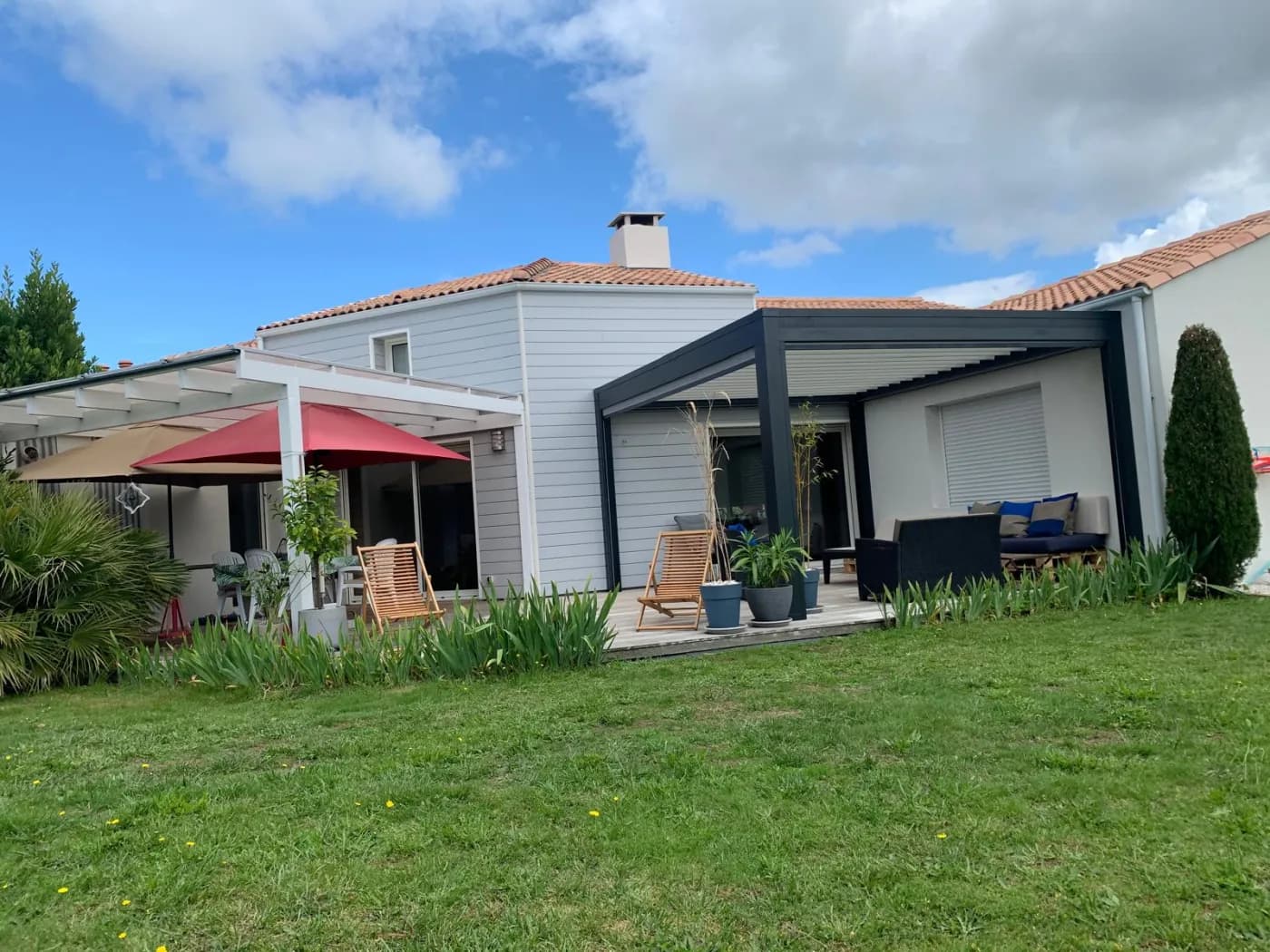 Pergola bioclimatique aluminium à lames orientables sur une terrasse avec salon de jardin